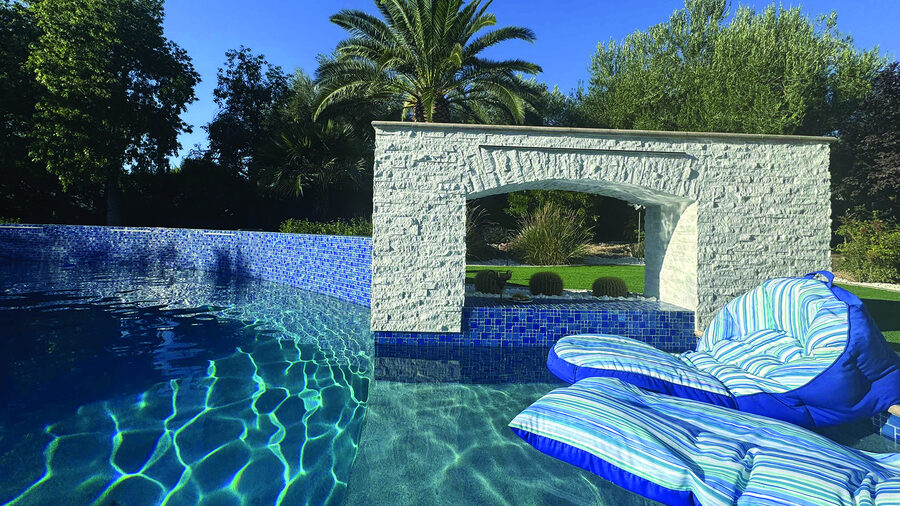 Loungers in the shallows, stone wall behind — EverClear Pools, the Las Vegas Valley